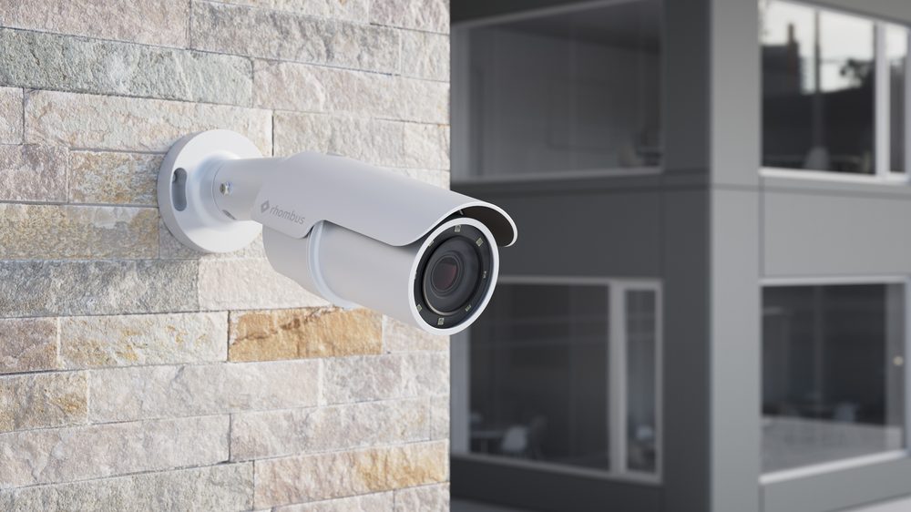 Rhombus R545 4K telephoto bullet camera mounted on a stone wall with office building backdrop